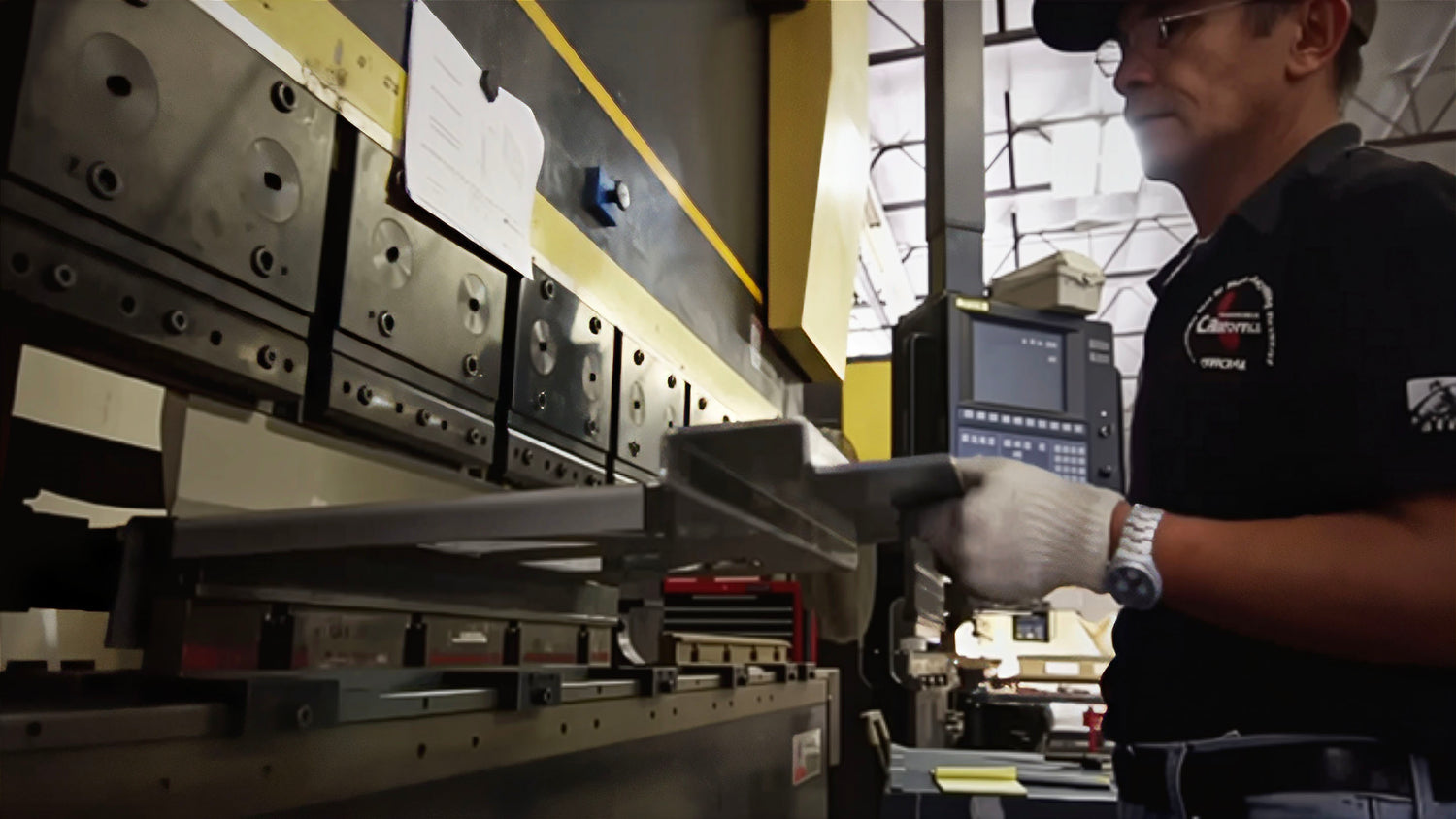 Man stamping a shape out of sheet metal on an industrial press